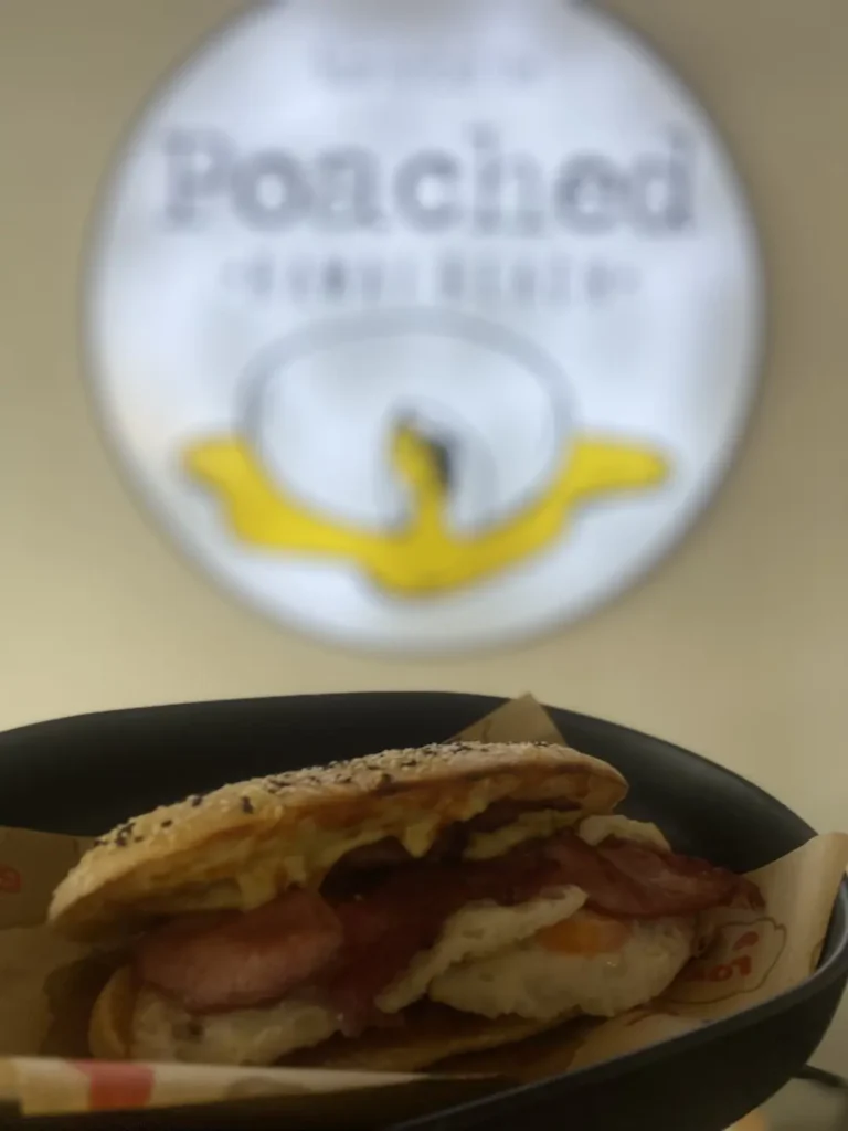 Bacon and egg sandwich in front of a blurry sign at one of the best indoor
attractions in Phuket: at Poached Breakfast Cafe , Chalong, Phuket, Thailand